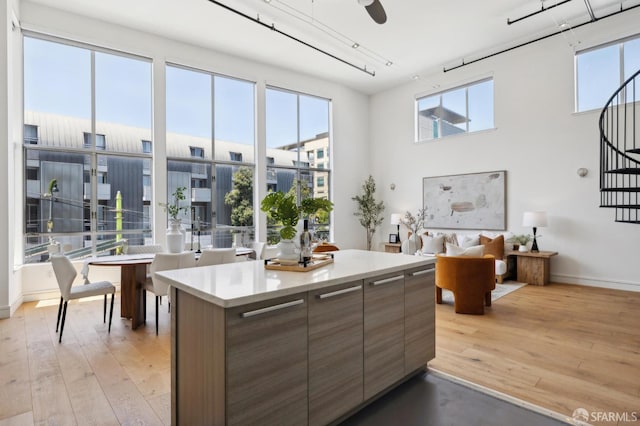 2011 3rd St Unit 6, San Francisco, CA 94107 - kitchen featuring modern cabinets, light wood-style floors, a center island, light countertops, and a high ceiling