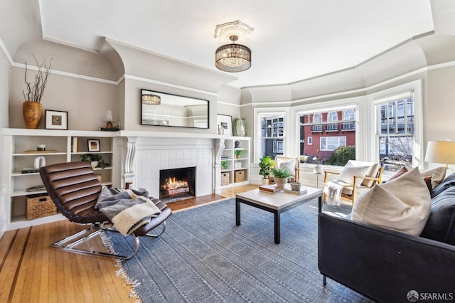 living room featuring crown molding, hardwood / wood-style floors, and a fireplace