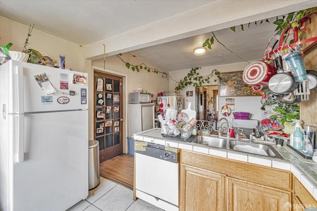 kitchen featuring sink, tile countertops, white appliances, light brown cabinetry, and light tile patterned floors