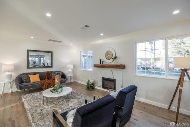 living room with a high end fireplace and light hardwood / wood-style flooring