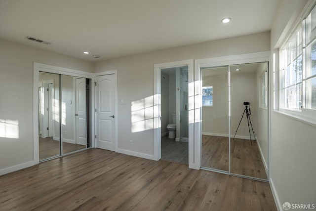 unfurnished bedroom with wood-type flooring and ensuite bath