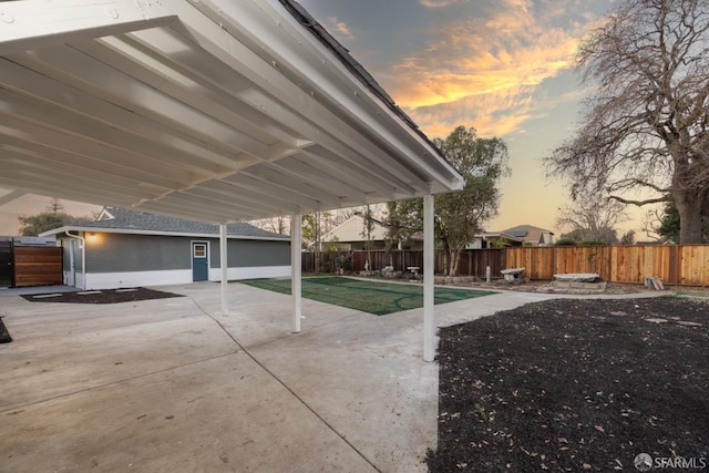 patio terrace at dusk featuring a lawn