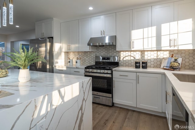 kitchen featuring stainless steel appliances, white cabinets, pendant lighting, and light stone counters