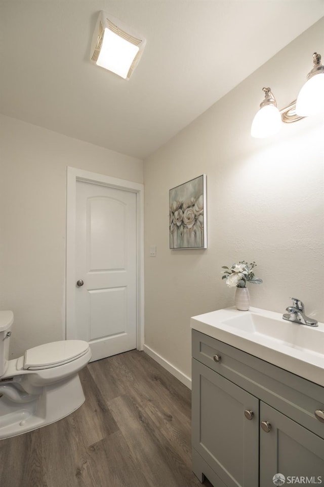 bathroom with toilet, vanity, and hardwood / wood-style flooring