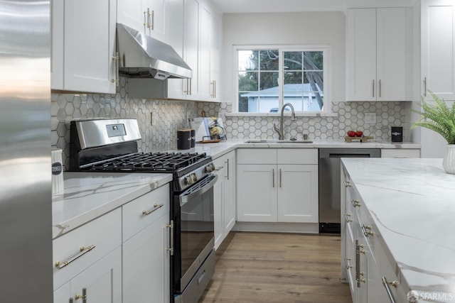 kitchen featuring appliances with stainless steel finishes, white cabinets, decorative backsplash, and sink