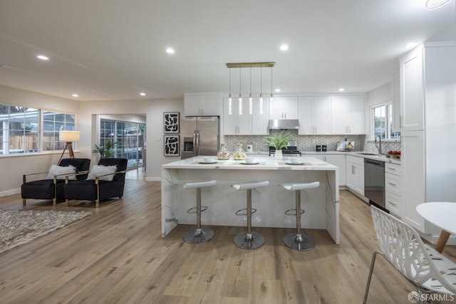 kitchen featuring white cabinetry, a center island, hanging light fixtures, and appliances with stainless steel finishes