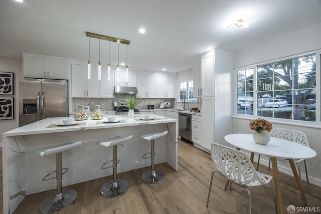 kitchen featuring a center island, hanging light fixtures, stainless steel appliances, white cabinetry, and sink