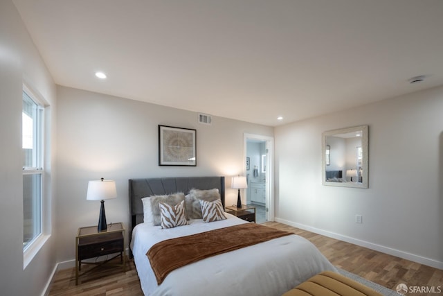 bedroom with connected bathroom and hardwood / wood-style flooring