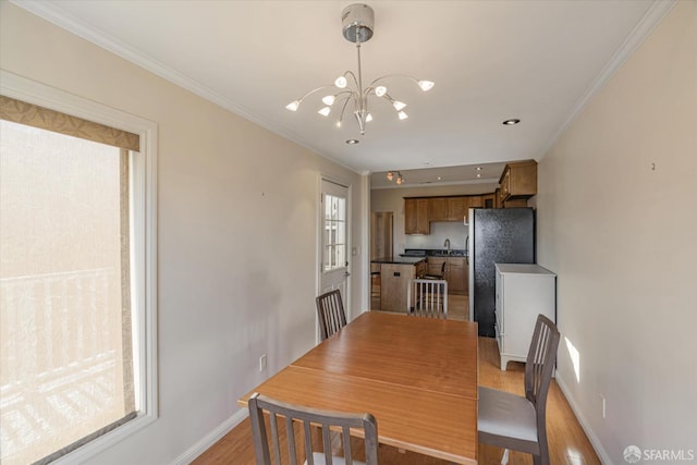 dining area featuring light hardwood / wood-style floors, an inviting chandelier, crown molding, and sink