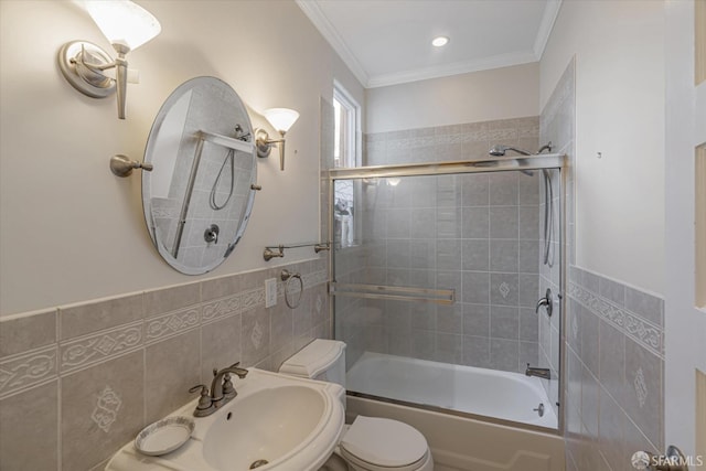 full bathroom with shower / bath combination with glass door, sink, toilet, ornamental molding, and tile walls