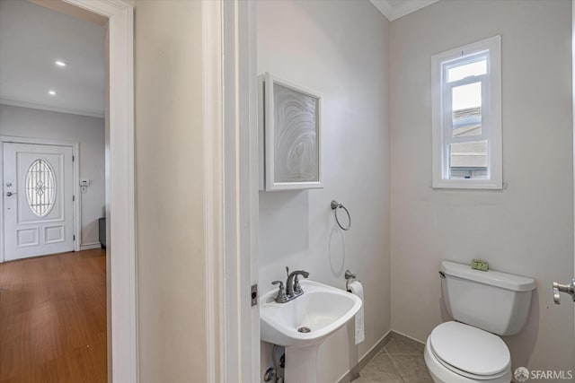 bathroom featuring toilet, tile patterned floors, ornamental molding, and sink