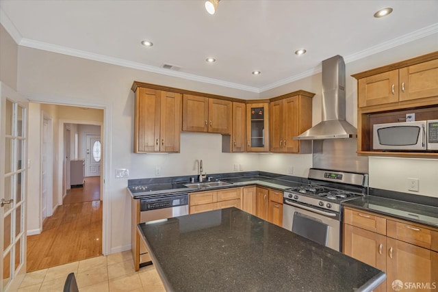 kitchen featuring sink, wall chimney range hood, crown molding, light tile patterned floors, and appliances with stainless steel finishes