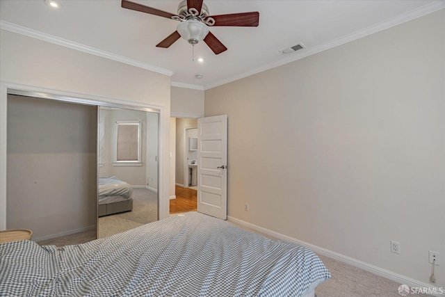 bedroom featuring ceiling fan, a closet, light colored carpet, and ornamental molding