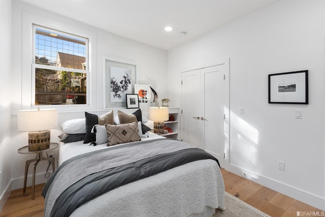 bedroom featuring light wood finished floors, a closet, recessed lighting, and baseboards