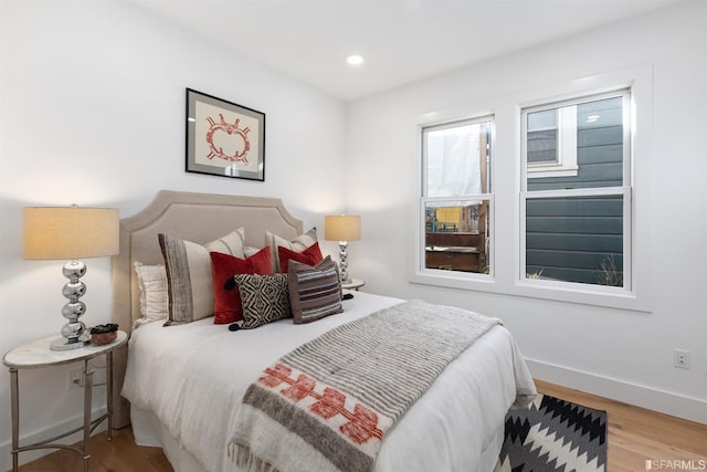 bedroom with baseboards, wood finished floors, and recessed lighting