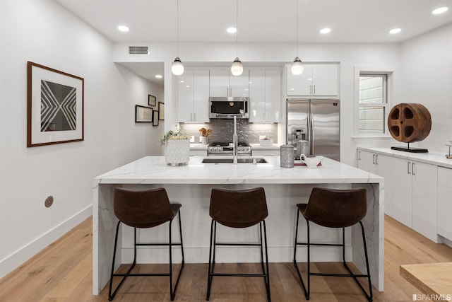 kitchen with stainless steel appliances, modern cabinets, visible vents, and white cabinetry