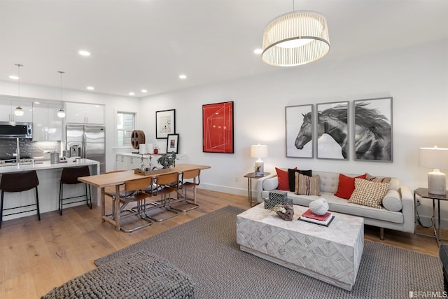 living room with baseboards, light wood-style flooring, and recessed lighting