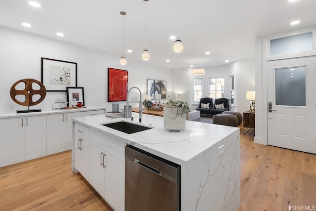 kitchen with a sink, white cabinets, stainless steel dishwasher, light wood finished floors, and pendant lighting