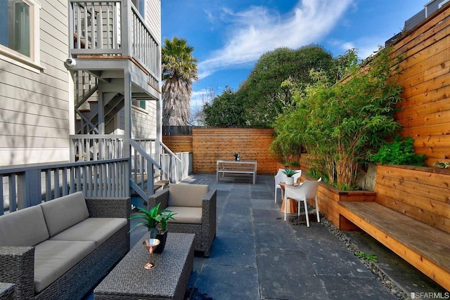 view of patio with a balcony, a fenced backyard, and an outdoor living space