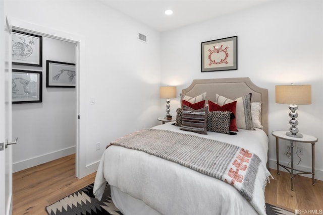 bedroom with recessed lighting, visible vents, baseboards, and wood finished floors