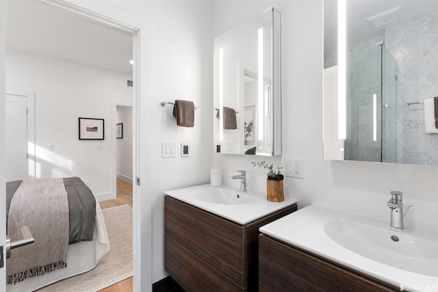 full bathroom with a marble finish shower, two vanities, and a sink