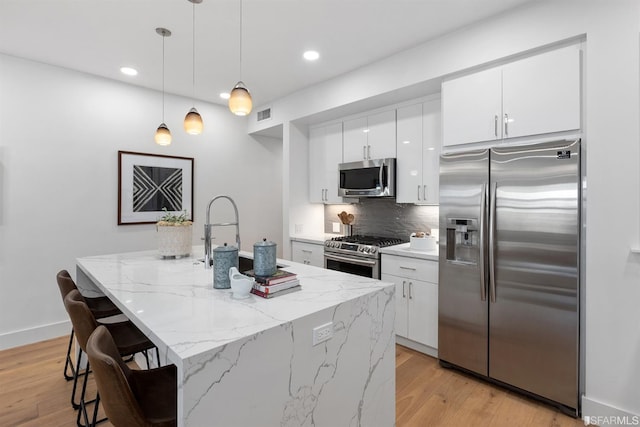 kitchen featuring appliances with stainless steel finishes, visible vents, white cabinets, and light wood-style flooring