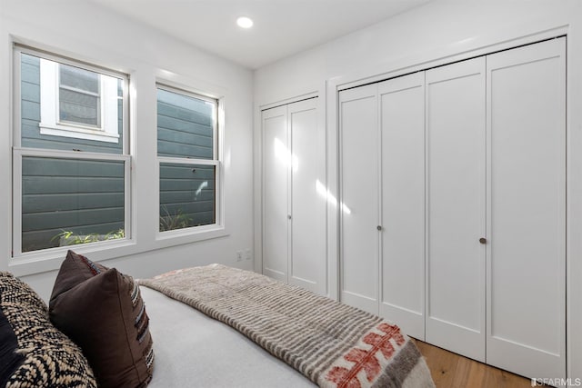 bedroom featuring light wood-style floors, recessed lighting, and multiple closets