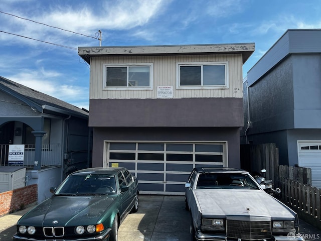 view of front of house with concrete driveway, a garage, and fence