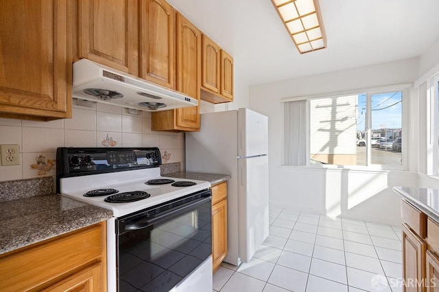 kitchen featuring electric stove, decorative backsplash, light tile patterned flooring, under cabinet range hood, and baseboards