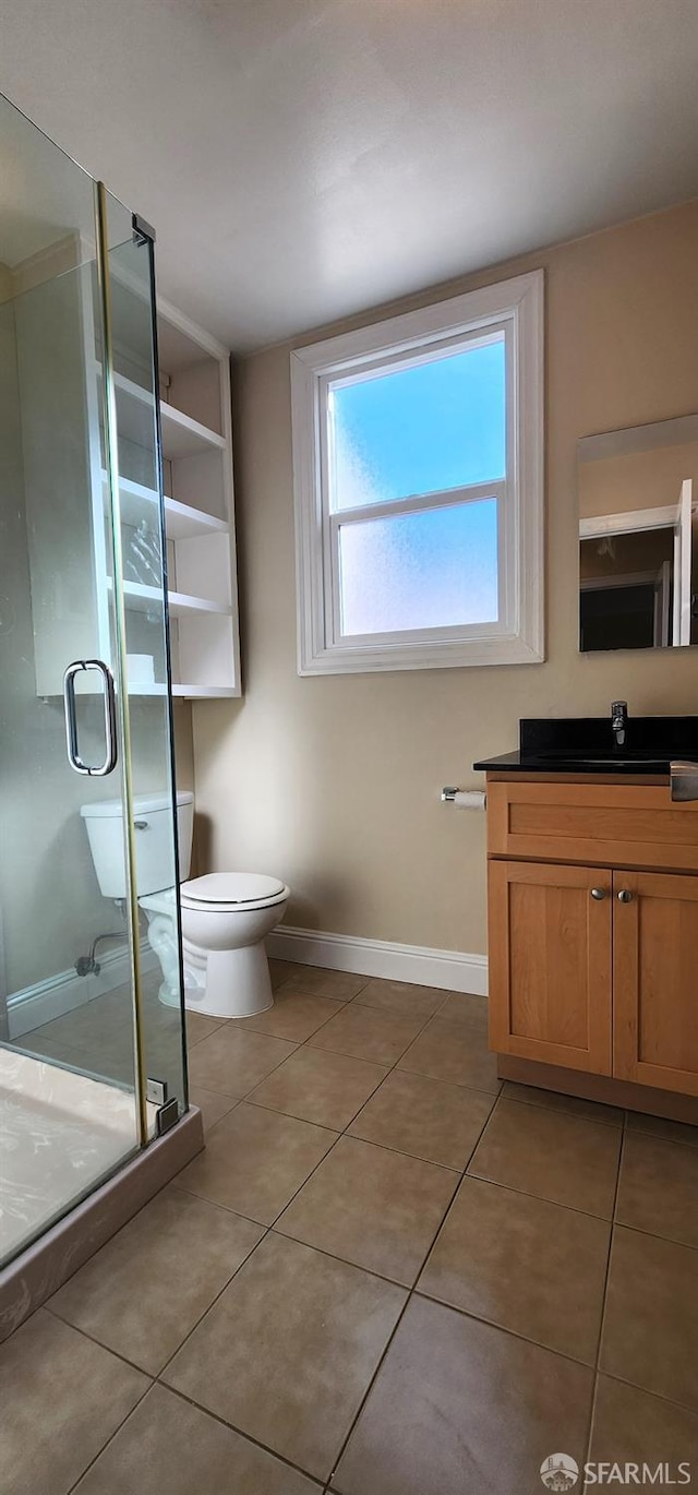 full bathroom featuring toilet, tile patterned floors, baseboards, and a shower stall