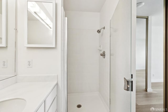 bathroom featuring vanity, hardwood / wood-style flooring, and a tile shower