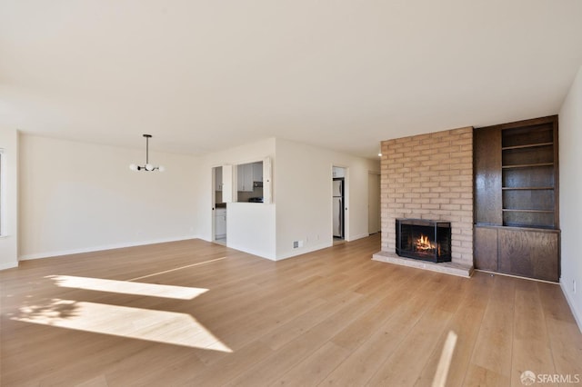 unfurnished living room with a fireplace, built in features, and light wood-type flooring