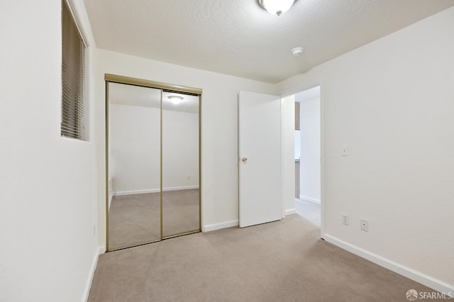 unfurnished bedroom with light carpet, a closet, and a textured ceiling