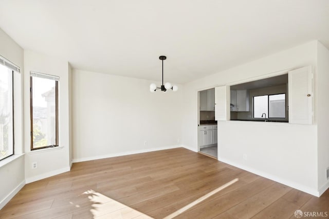 spare room featuring a chandelier, sink, and light wood-type flooring