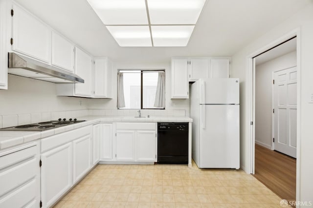 kitchen with white refrigerator, white cabinetry, black dishwasher, and tile countertops