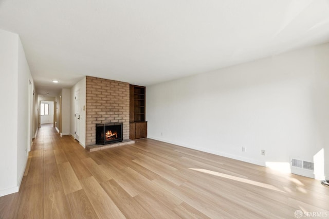 unfurnished living room featuring a brick fireplace and light hardwood / wood-style floors