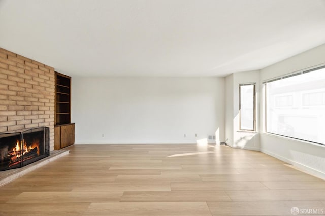 unfurnished living room with a fireplace and light hardwood / wood-style floors