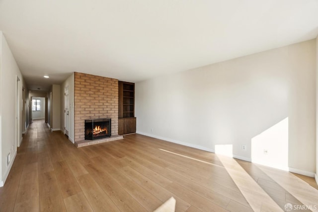 unfurnished living room featuring a brick fireplace and light hardwood / wood-style flooring