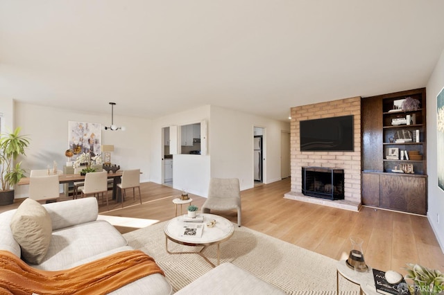 living room with built in shelves, a fireplace, and light hardwood / wood-style flooring