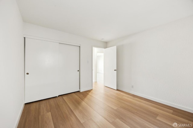 unfurnished bedroom featuring a closet and light wood-type flooring