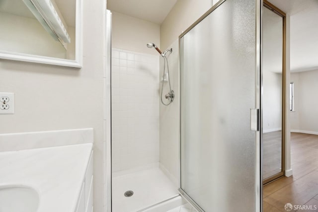 bathroom featuring walk in shower, vanity, and wood-type flooring