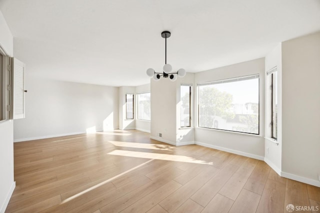 unfurnished living room with a chandelier and light hardwood / wood-style flooring