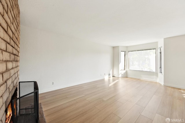 unfurnished living room featuring a multi sided fireplace and light hardwood / wood-style flooring