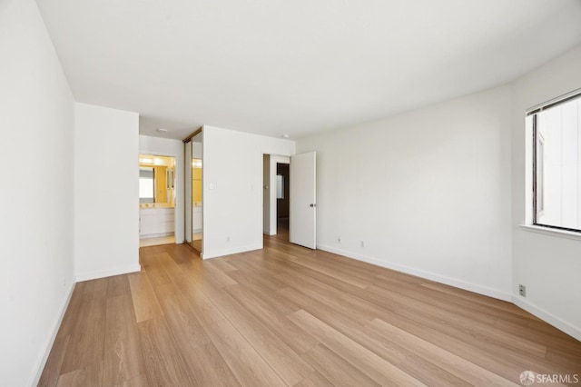 unfurnished bedroom with light wood-type flooring and ensuite bath