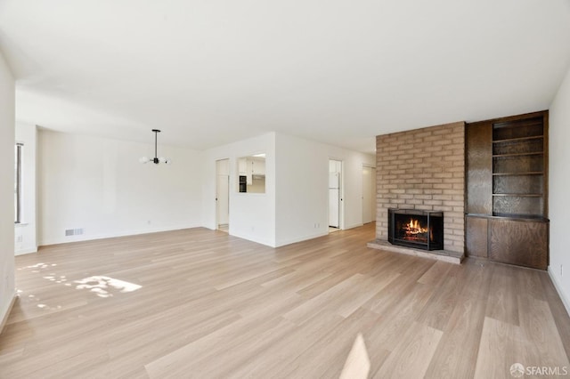 unfurnished living room with a brick fireplace and light hardwood / wood-style flooring