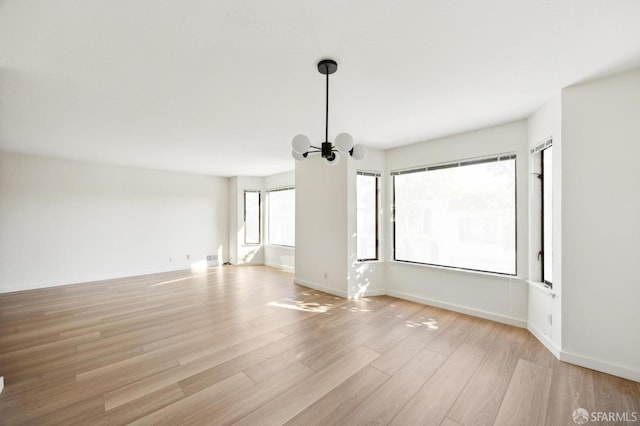 unfurnished room featuring a notable chandelier and light hardwood / wood-style floors