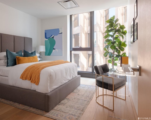 bedroom featuring a wall of windows, visible vents, and wood finished floors