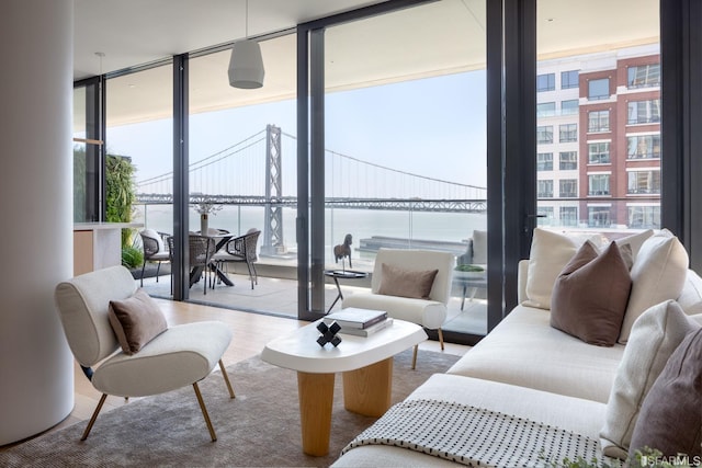 living area featuring a wall of windows, a water view, and wood finished floors