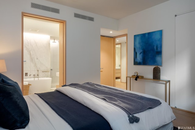 bedroom featuring ensuite bath, wood finished floors, and visible vents