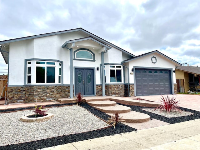single story home with an attached garage, concrete driveway, stone siding, and stucco siding